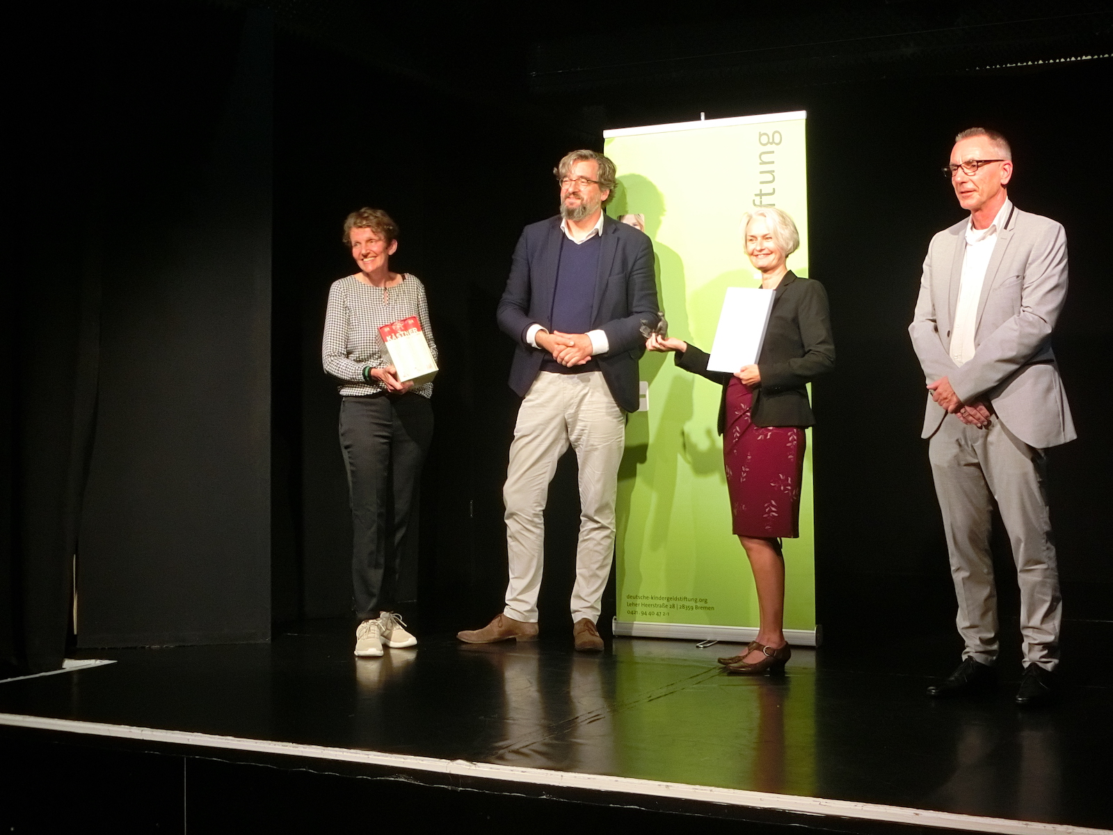 Andrea Merrath und Stephan Wegner von der Oberschule In den Sandwehen, Bertold Frick von der Deutschen Kindergeldstiftung und Heike Müller vom Virtuellen Literaturhaus auf einer Bühne