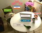 Das Poedu Team: Ein Kind mit Maske vor einem Tisch mit Laptop, verziert mit Emojis